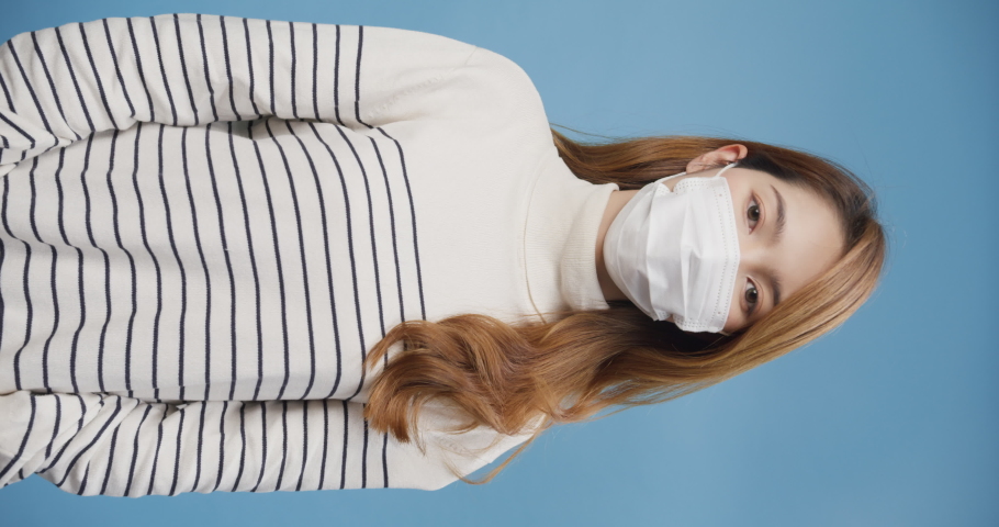Youth Asia lady wear sweater take off protective mask  breathing deep fresh air relax due coronavirus pandemic stand isolate on blue background. End of quarantine, Carefree concept. Vertical screen. | Shutterstock HD Video #1090371527