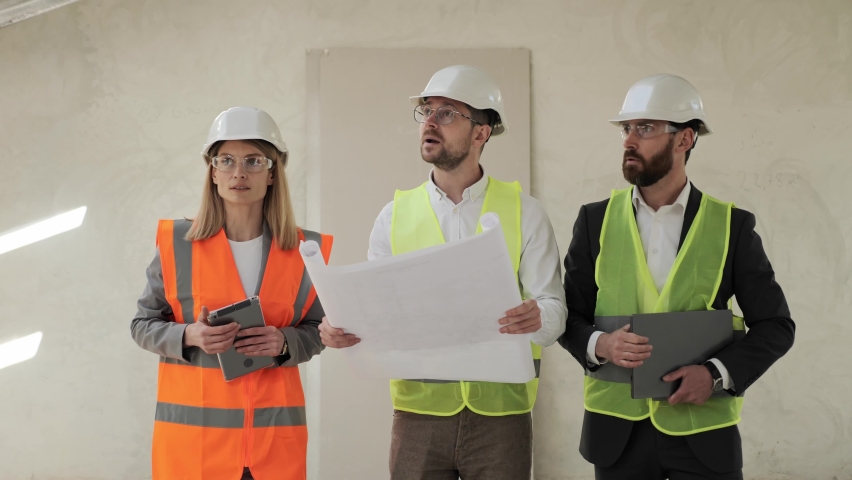Group of businesspeople and engineer inspecting real estate. Investor, architect, engineer analyzing and discuss the plan of construction site wearing a safety helmets. Finish Industrial Building.