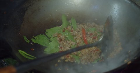 close up of chef cooking hot and spicy stir frying minced pork with thai holy basil in frying pan, Pad Krapow is one of the most favorite thai street food, Thai cuisine dish