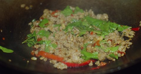 close up cooking hot and spicy stir frying minced pork with thai holy basil in frying pan, Pad Krapow is one of the most favorite thai street food, Thai cuisine dish