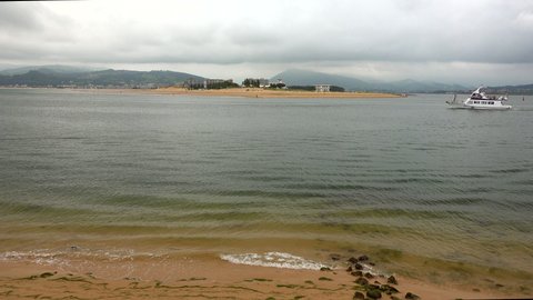 The Puntal de Laredo from Santoña with passenger boat crossing, Cantabria, Spain