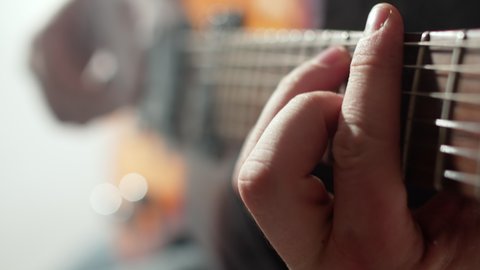 Male musician plays an electric guitar with plectrum in studio, closeup hands. Closeup of an electric guitar string played by musician using mediator