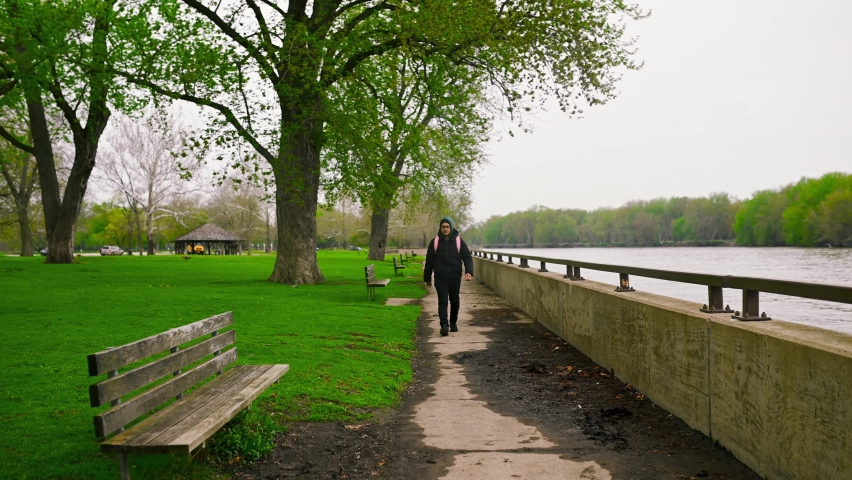 Man Walking On A Path Next To Illinois River And Sits Down On A Bench.