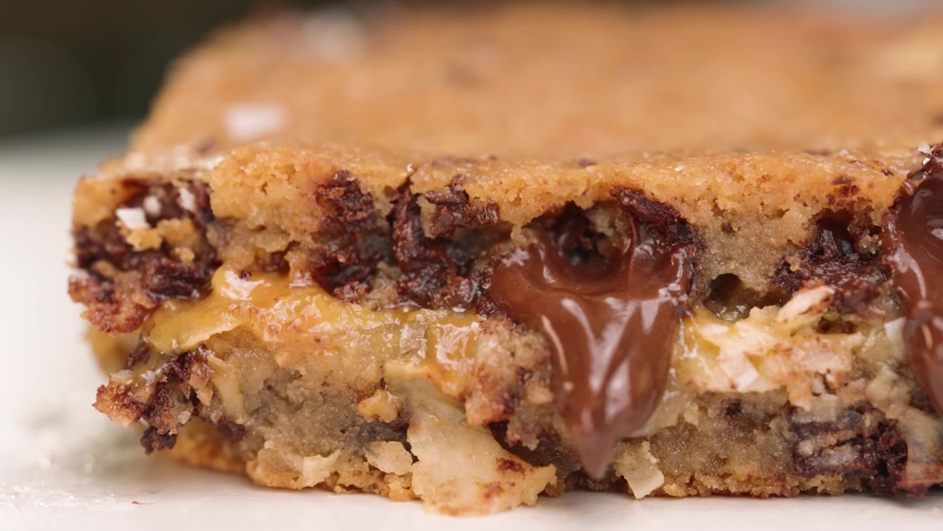 Macro close up of gooey blondie brownie with melted chocolate 4k pan left caramel and coconut