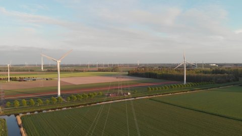 Red Tulip Field With View Of Wind Turbines And Electricity Pylons And Cables In Flevoland, Netherlands. aerial drone
