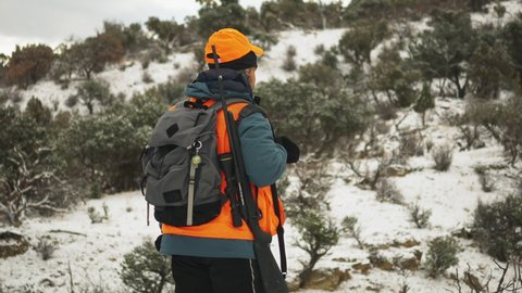 Hunter looking at a snowy scrubland wilderness preparing to aim.