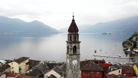 Aerial flyover around the belfry tower of the Chiesa dei Santi Pietro e Paolo church and over the rooftops Ascona, Switzerland along the shores of Lago Maggiore
