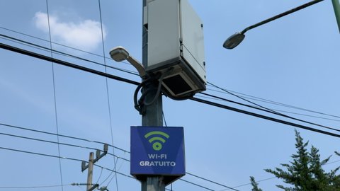 Free WIFI Sign On Lamppost In Mexico City With Street Light And Wires In Background Against Blue Sky
