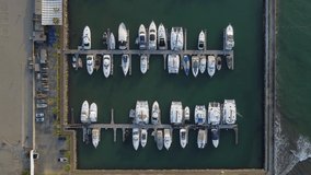 Topdown drone video of a marina where many boats are docked or parked. Recorded while slowly flying forward.