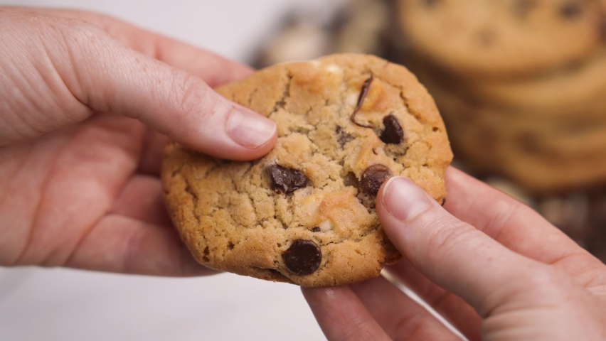 Tearing a warm chocolate chip cookie, gooey chocolate chips pulling apart with two hands close up slow motion 4k | Shutterstock HD Video #1090380097