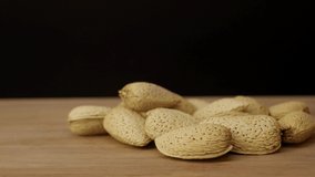 Nuts on a wooden table on a black background. Filmed on cinema camera, slow motion. 8K downscale, 4K.