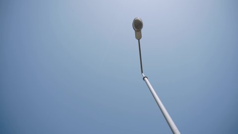 Upward view of old iron lamppost against clear blue sky on sunny day. Glass ceiling of lantern on a gray pole. Lighting equipment of the streets in the city.