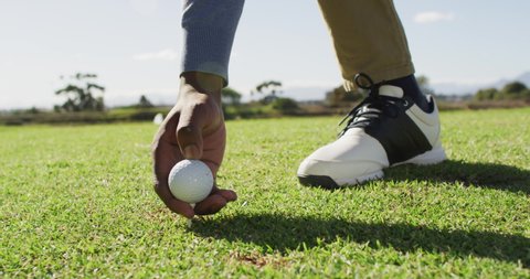 Video of hands and legs of african american man playing golf on golf field. sporty, active lifestyle and playing golf concept.