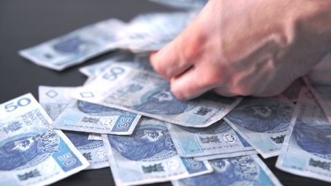 Men's hands scrape scattered banknotes from the table.