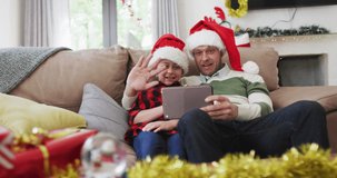 Animation of snow falling at chrsitmas over happy caucasian father with son having video call. christmas and celebration concept digitally generated video.