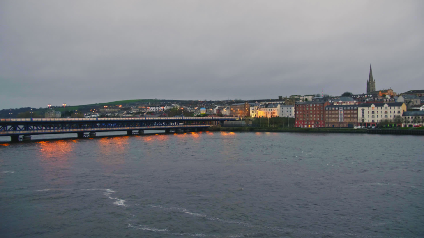 View at dawn across peaceful river Foyle towards traffic crossing Craigavon Bridge at St. Columb