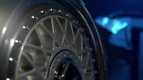 Close up view of three-piece forged silcer color wheels with classic pattern. Beautiful rims with chrome-plated shiny shelf with perfect polished bolts are spinning.