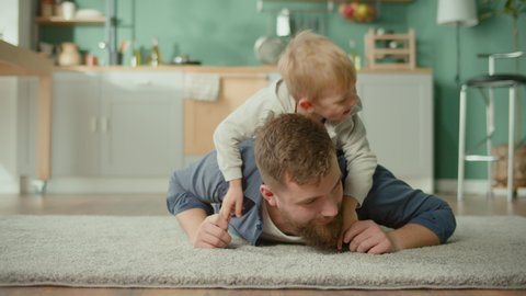 A Best Dad and Son Spending Time Together. Boys are Playing on the Floor. Happy Family Time. Enjoying of Each Other. Father's Day. Super Dad. Positive Loving Stay-at-Home Bearded Father