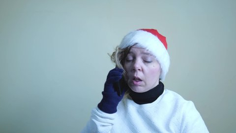 A forty-year-old woman in a red New Year's hat and a white sweater. A blonde woman is talking on a cell phone. slow motion