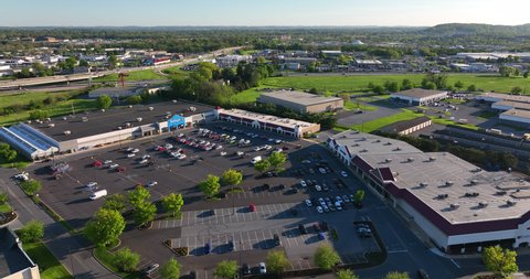 Lancaster , PA , United States - 05 14 2022: High aerial rotating shot of commercial shopping area. Large parking lot. Walmart sells goods during springtime.
