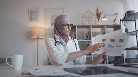 Medical charts. Health insurance. Clinical investment. Serious woman doctor discussing analysis report statistics graphs at webinar video call meeting at hospital. - Powered by Shutterstock - Get 15% off with code: PIKWIZARD15