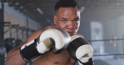 Video of fit african american man boxing at gym. active, fit, sporty and healthy lifestyle, exercising at gym concept.