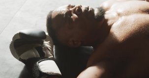 Video of fit and tired african american man resting after box training at gym. active, fit, sporty and healthy lifestyle, exercising at gym concept.