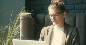 Young startup woman works and studies on tablet, Female sitting in cafe with coffee cup. Girl in glasses in pause, after work. Online chat. 4K video Slow motion.