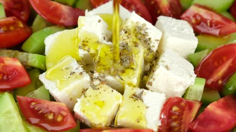 Feta cheese and vegetables. Pouring olive oil on salad with feta cheese, tomatoes, cucumber. Healthy food concept