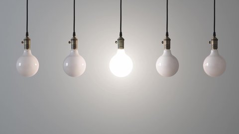 Five energy-saving light bulbs hang on a gray background. The central one lights up with a matte light. Can be used for background. Light bulbs don't move