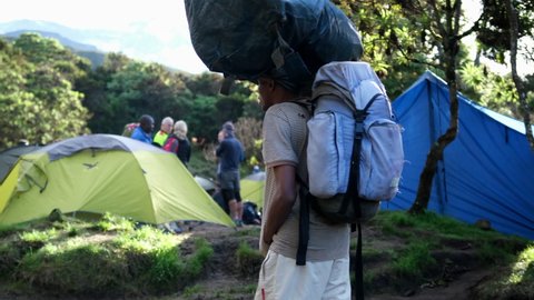 Porters with large backpacks with equipment leave the Machame camp during the ascent of Mount Kilimanjaro