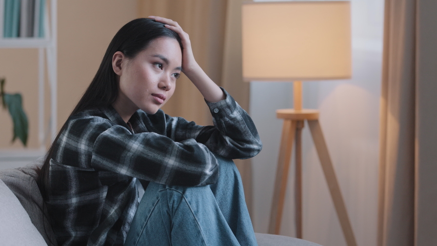 Alone tired boredom sad Asian woman exhausted girl sitting on couch at home feeling unsure unhappy sadness bad feeling mental trouble psychology trouble depressed desperate pensive Korean girl think | Shutterstock HD Video #1090404609