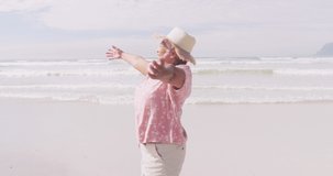 Animation of light spots over happy senior african american woman dancing on sunny beach. healthy and active beach holiday concept digitally generated video.