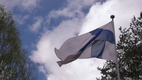 Finnish flag waving in the wind slow motion close up video with blue sky and clouds in the background.
