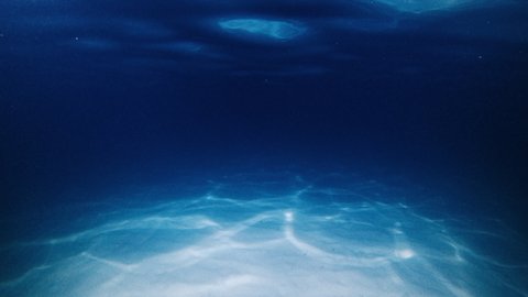 Night sea. Underwater view of the night sea and sandy bottom with wave and ripples