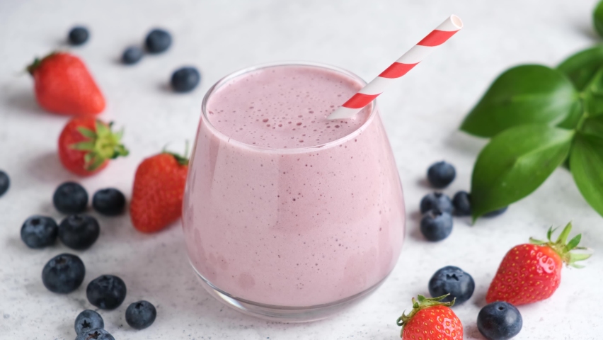 Berry fruit smoothie in glass with drinking straw. Healthy drink, pink smoothie or cocktail