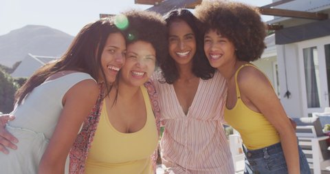 Portrait of happy diverse female friends embracing and smiling at swimming pool party. spending quality time at home.