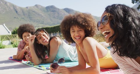 Happy diverse female friends talking and smiling at swimming pool party. spending quality time at home.