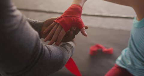 Video of hands of diverse woman and man tying tapes, preparing for box training at gym. active, fit, sporty and healthy lifestyle, exercising at gym concept.