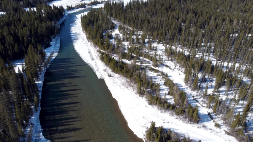 Drone fly through the frozen Bow River valley forest in winter. Snow capped Canadian Rockies mountain range. Aerial panorama view. Canmore, Alberta, Canada. Royalty-Free Stock Footage #1090411813