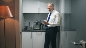 Mature businessman make coffee in office kitchen and use smartphone. Corporate worker use coffee machine at workplace - Powered by Shutterstock - Get 15% off with code: PIKWIZARD15