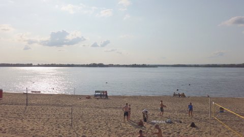 Samara, Russia - circa April, 2022: A group of people playing beach volleyball on the sand on the bank of a big river