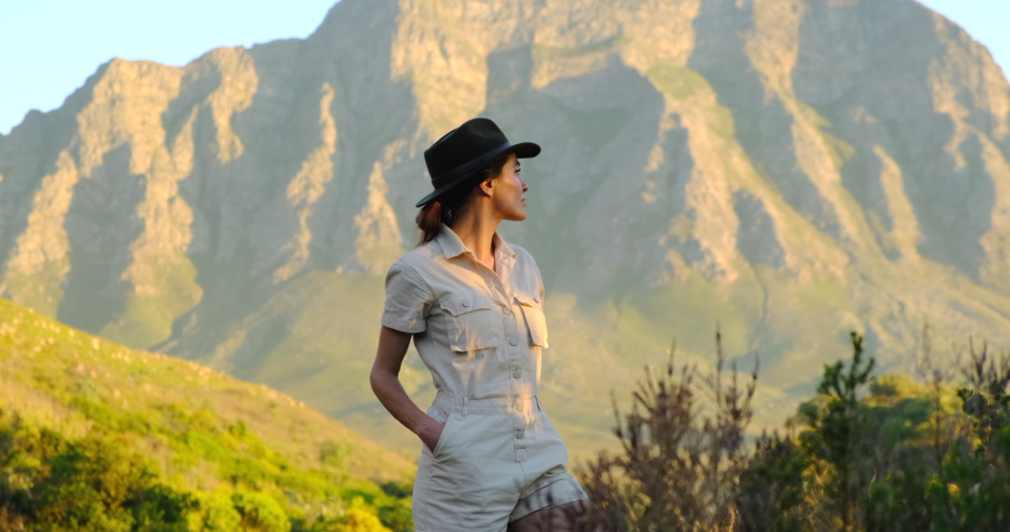 Inspiring female traveler and travel blogger looks around herself, enjoying the height of the mountains and the sunset. Outdoor portrait happy female tourist having good time wandering around nature