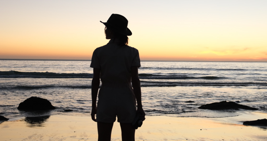 Raises arms into air, happy and drunk on life, youth and happiness. girl alone with nature relax sunset concept. silhouette of a girl traveler at sunset on the ocean in usa. woman breathing fresh air | Shutterstock HD Video #1090416067