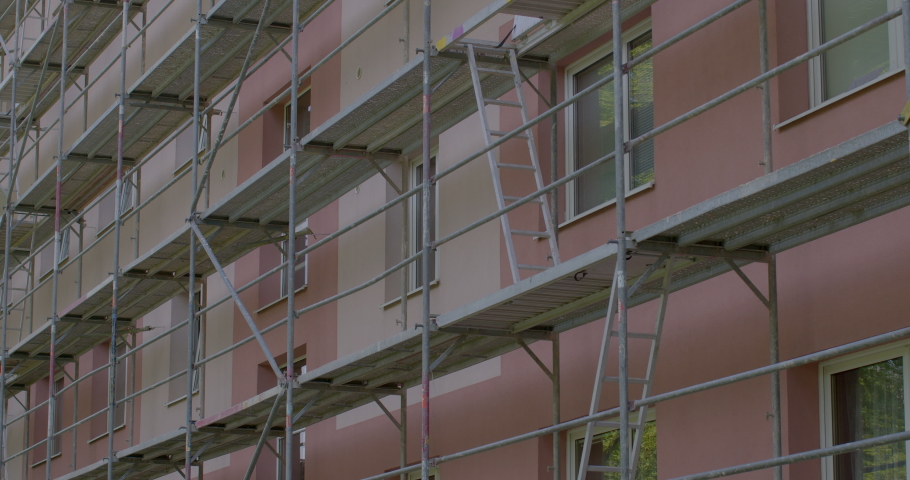 Facade of building is set with scaffolding construction work. Passages fixed along floors for assembly work transportation of building materials. Renovation project scaffolding construction equipment  Royalty-Free Stock Footage #1090417507