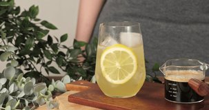 4k video slow motion stock footage, woman used hands pouring cold drink. Glass of espresso short with iced lemon juice and lemon slices in cup, Summer Cocktail, Cold brew coffee or black tea.