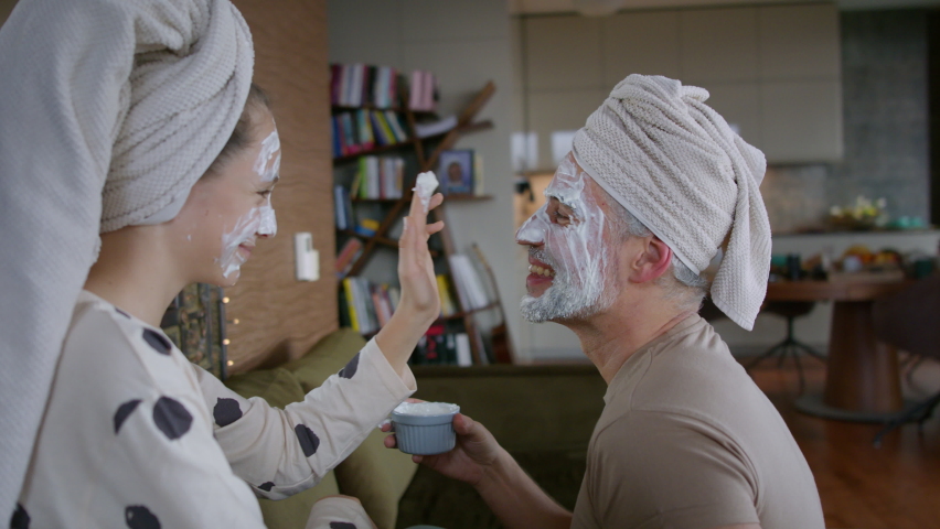 Teenage daughter applying face mask to her father at home