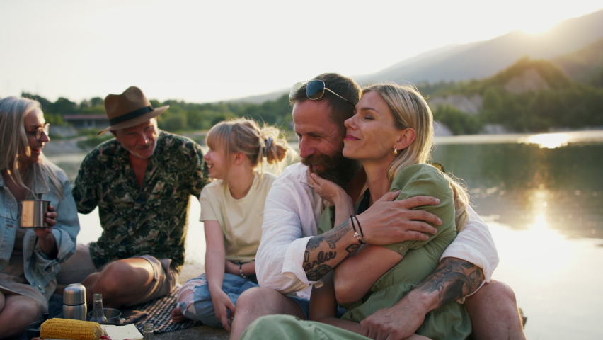 Happy multigeneration family on summer holiday trip, barbecue by lake.