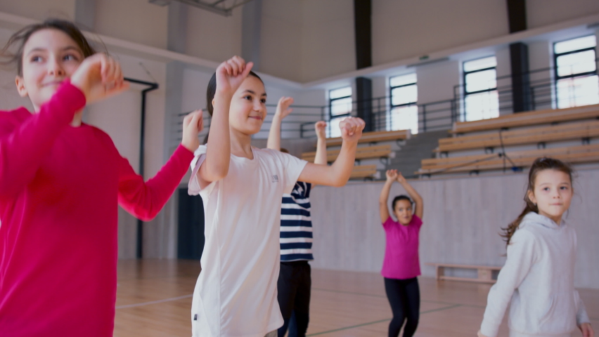 Group of elementary students exercising during class at school gym. Royalty-Free Stock Footage #1090418043
