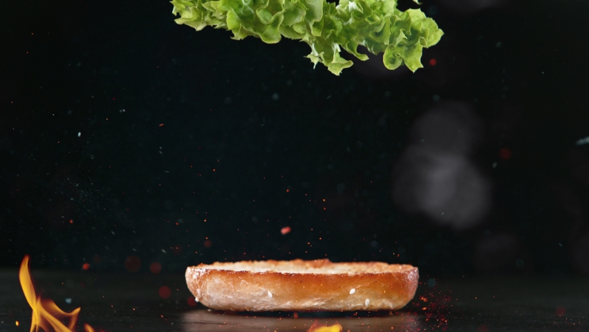Beef Burger Ingredients Falling and Landing in the Bun with Fire Flames. Super Slow Motion at 1000 fps. Royalty-Free Stock Footage #1090419749